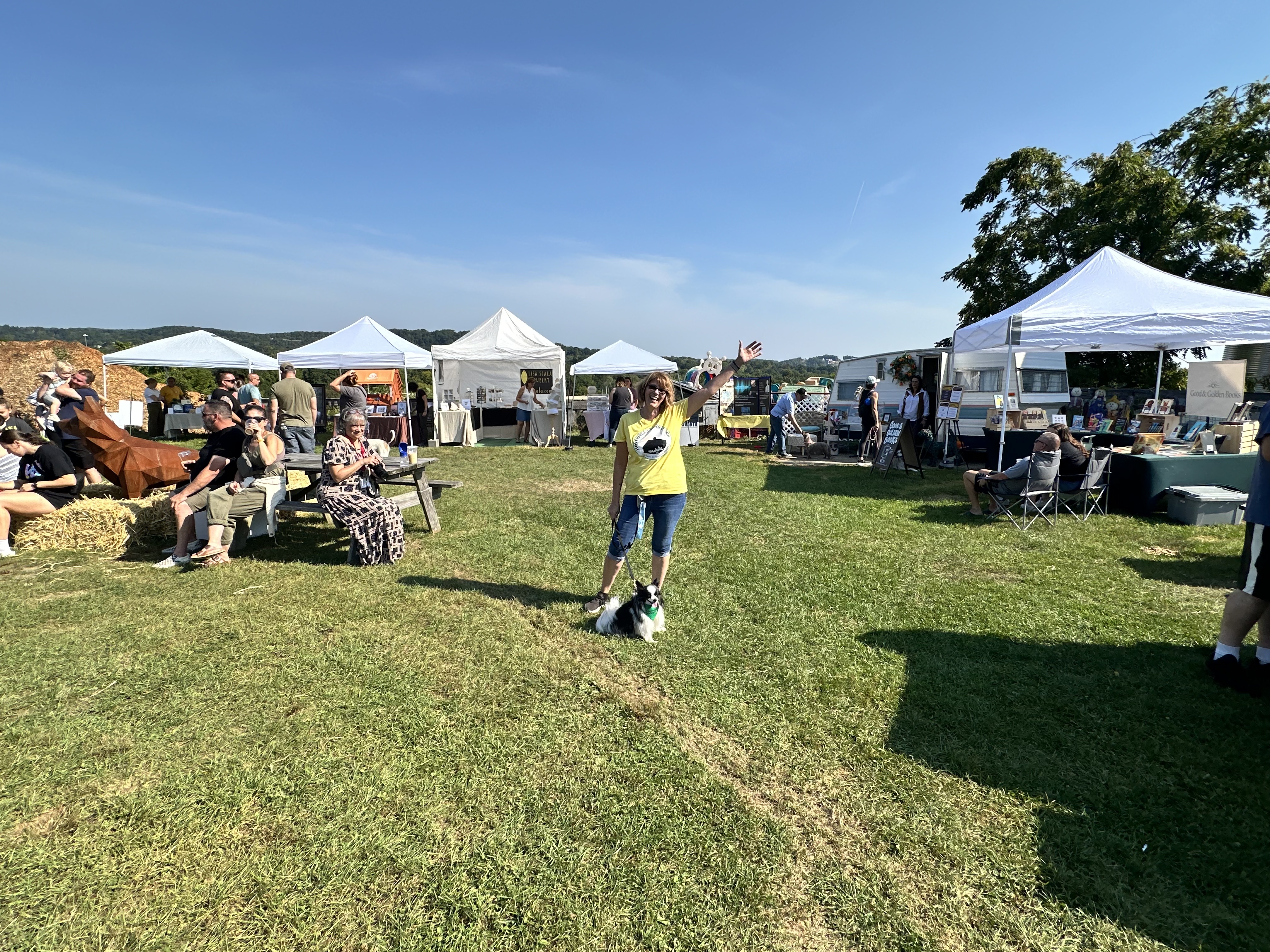 Event Organizer Cyndie Morgan celebrating with her dog Nigel at the inaugural event of Haverhill's Woofstock.  She is standing in the middle of all the vendor booths.